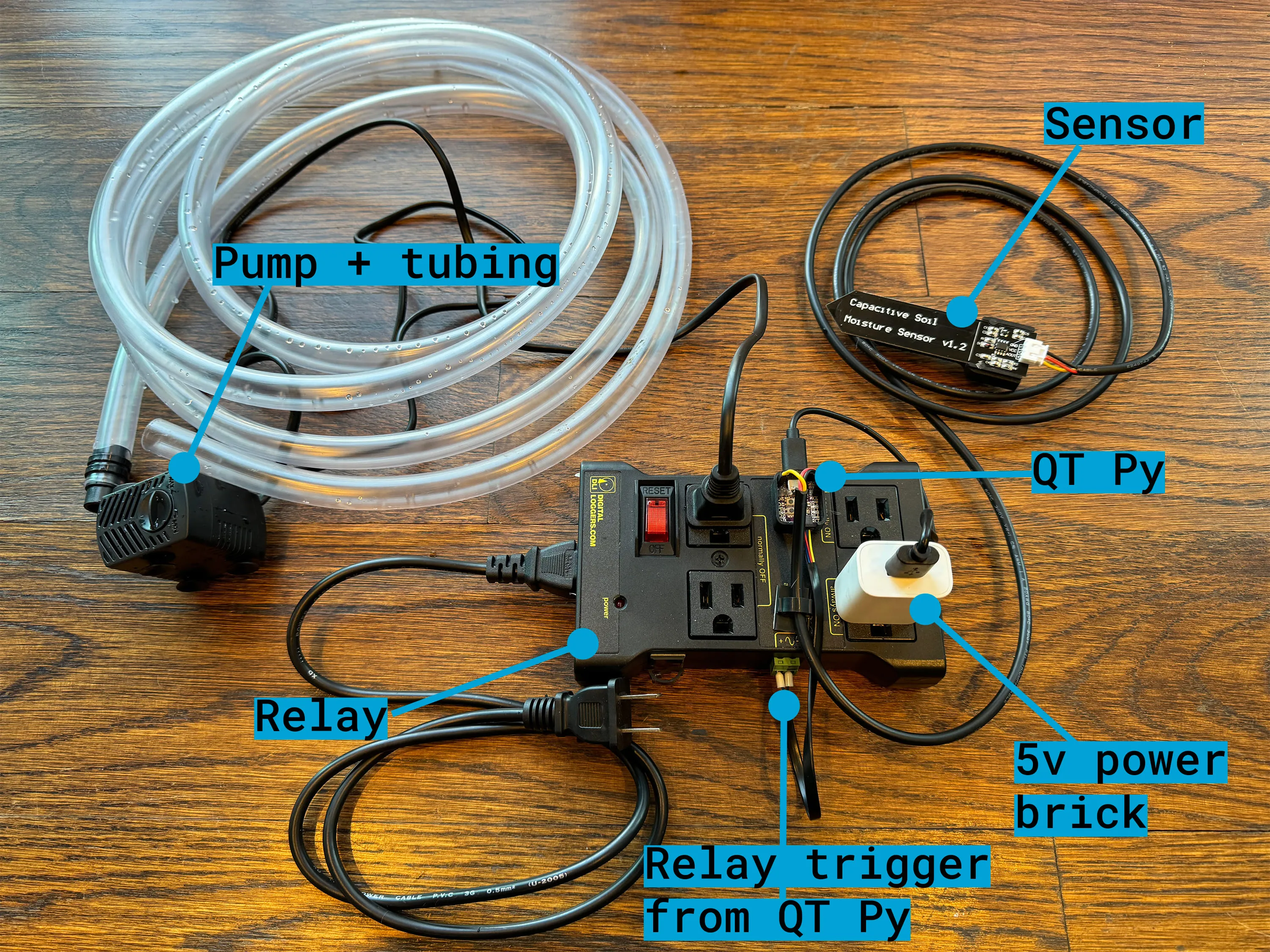 Overhead view of the power relay, QT Py, moisture sensor, pump, and tubing connected together